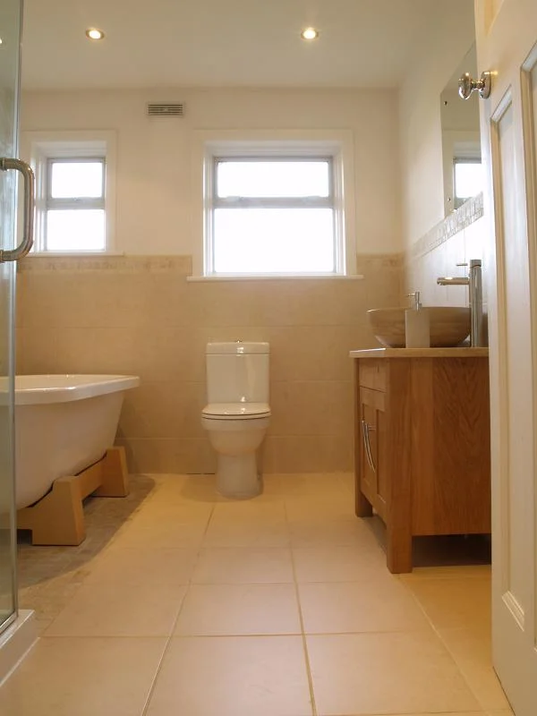 Bathroom installation Ealing — view from doorway showing roll-top bath, toilet, oak vanity unit with stone vessel basin